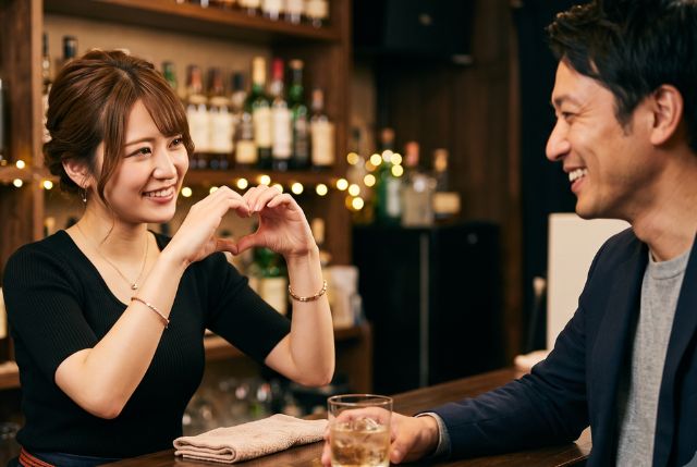 男性客にハートを向けるバーテンダーの女性