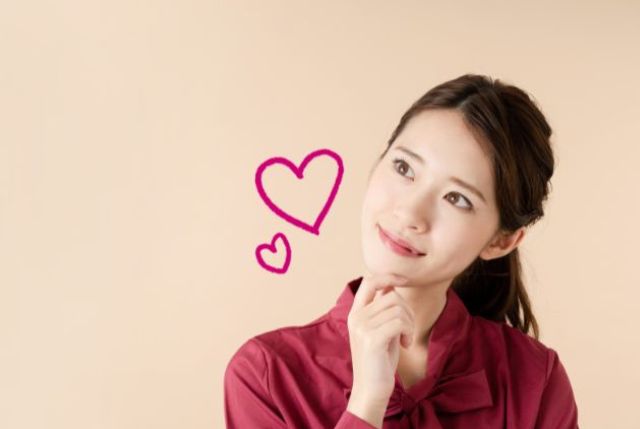 顎に手を当てて首を傾げる女性とハートマーク