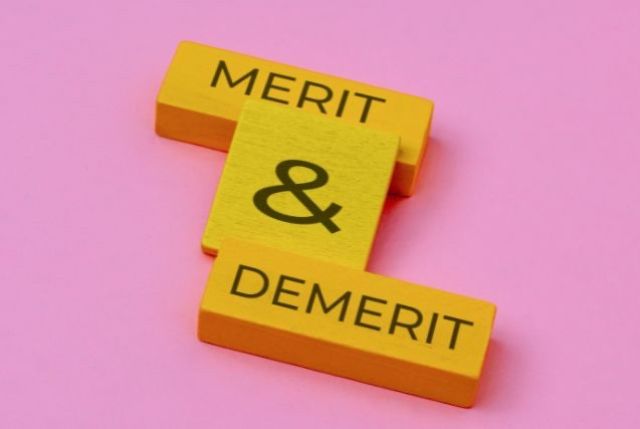 ピンクのテーブルの上にmerit & demeritと書かれた木のブロック