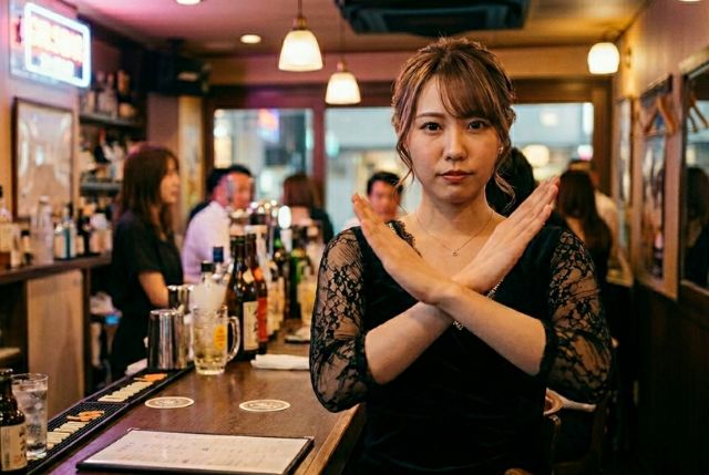 バーの中で腕をクロスする若い女性