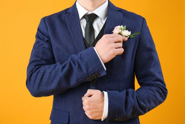 スーツを着て胸元に花を刺す男性の手元