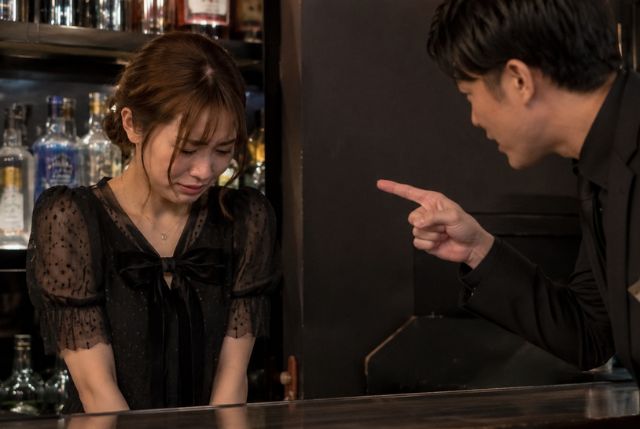 困った表情の女性に指差しながら話しかける男性