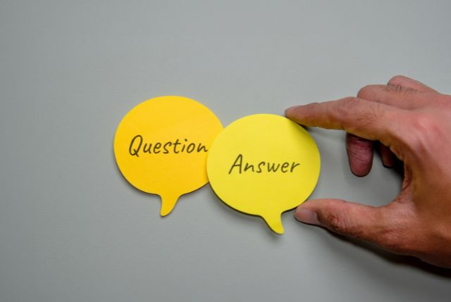 Questionと書かれた吹き出しとAnswerと書かれた吹き出しを持つ男性の手