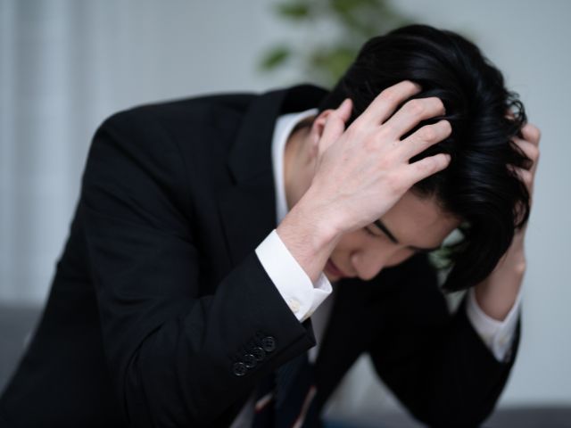 頭を抱えるスーツ姿の男性