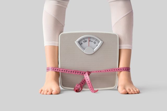 体重計を足に挟んでいる女性