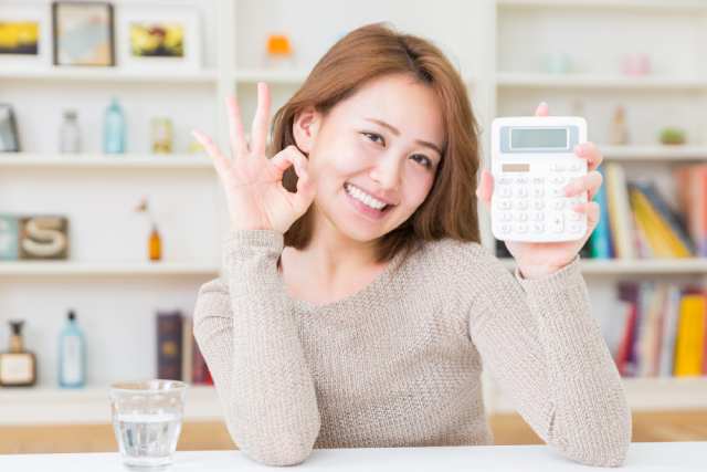 電卓を持って笑顔を見せる日本人の若い女性