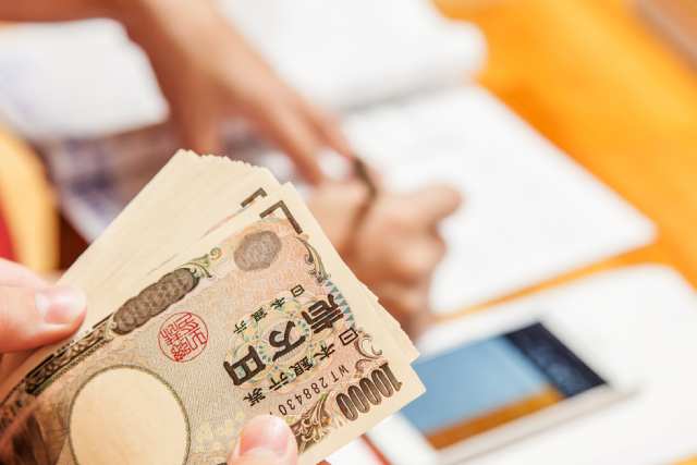 一万円札の束を数える女性の手元