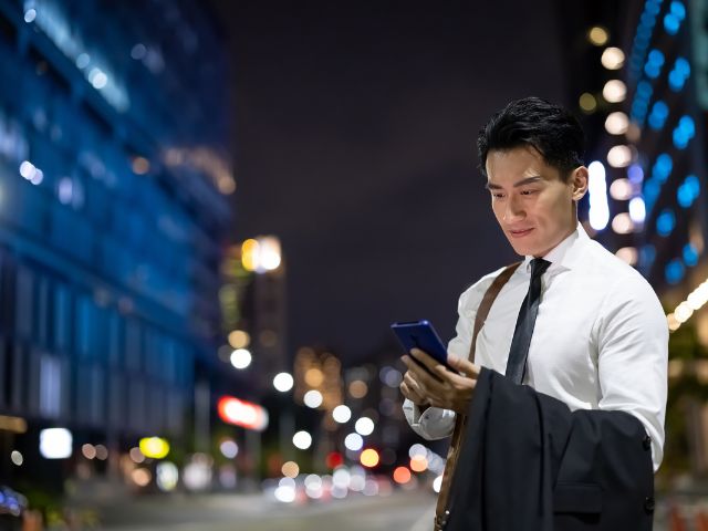 街の中でスマホを持っているサラリーマン風のスーツ姿の男性