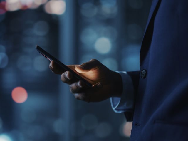 スーツを着てスマホを持つ男性の手元
