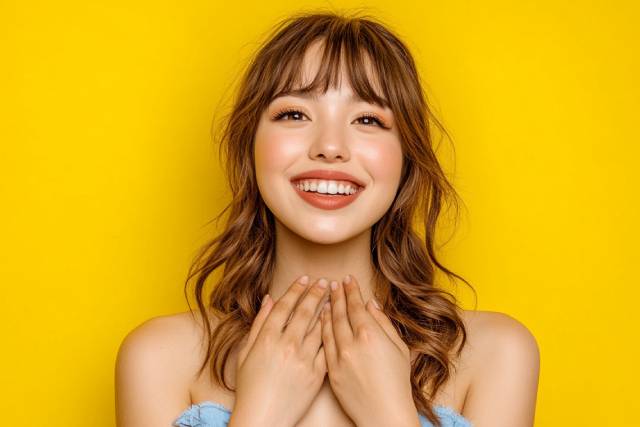 黄色い背景の前で何かを貰って喜んでいる女性