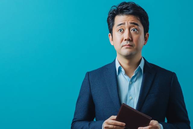 青い背景の前でお財布を持って悲しんでいる男性