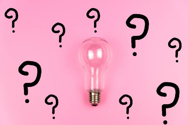 ピンクの背景にピンクの電球と複数のクエスチョンマーク