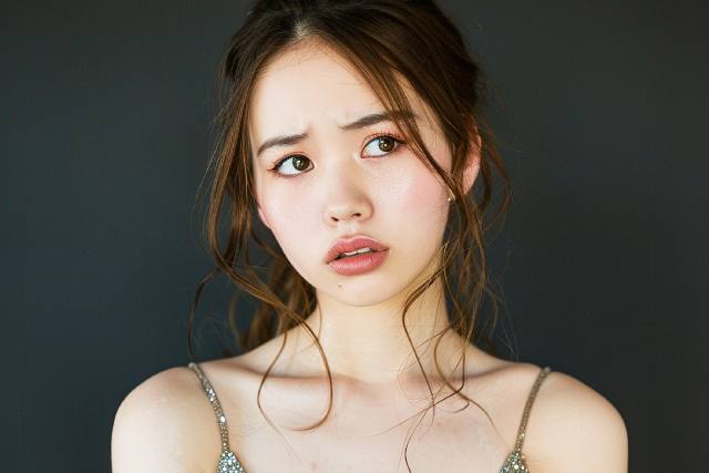 嫌そうな表情をうかべるドレス姿の若い日本人女性