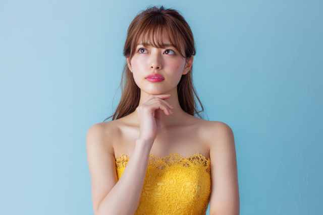 水色の背景の前で何かを考えている女性