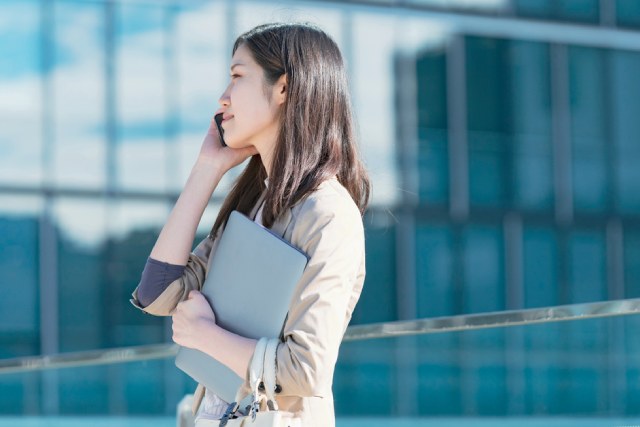 外まわり営業中に電話をかけるスール姿の女性