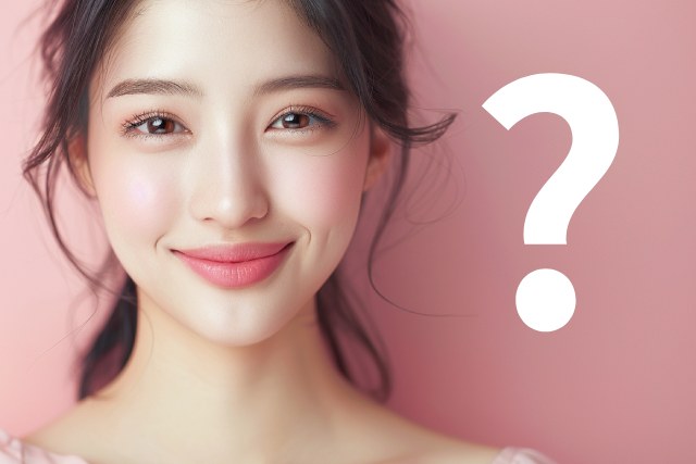 ピンクの背景と微笑む日本人の女性とクエスチョンマーク
