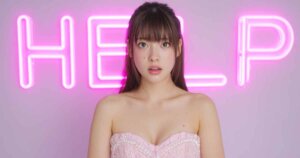 HELPと書かれたネオンの前にいるドレスの女性