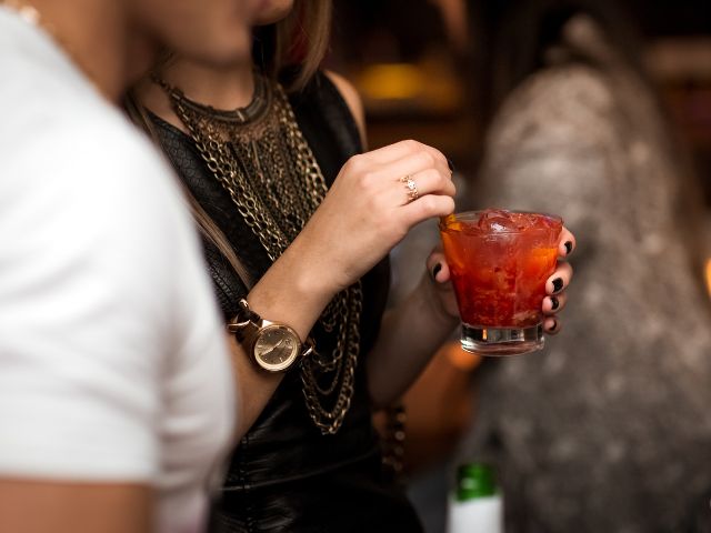 黒いドレスの女性がお酒を持ちながら男性と話している