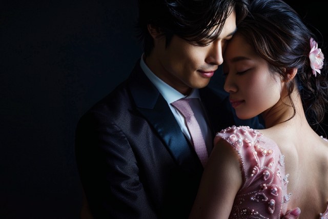 スーツを着たハンサムな日本人の男性がピンクのドレスを着た美しい日本人の女性の背中を抱きしめている様子