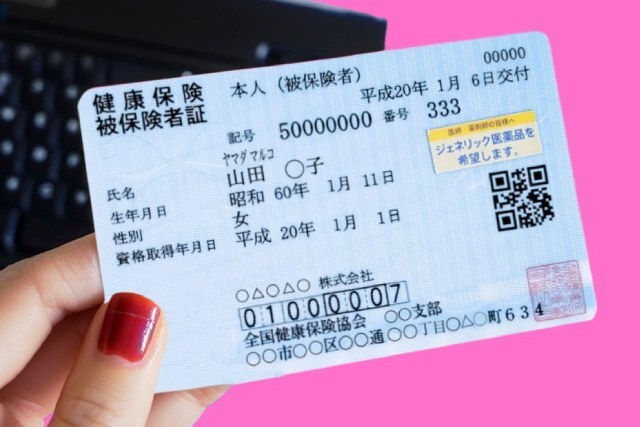健康保険証を持つ女性の手