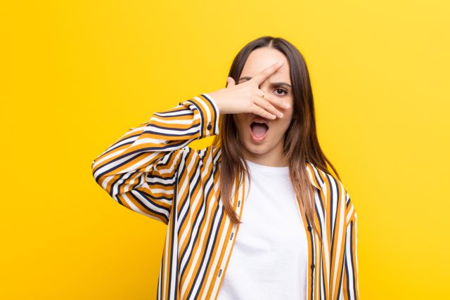 目を手ですこし隠す女性