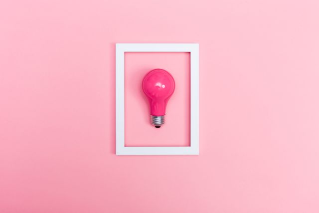 ピンクの背景にある白い枠とピンクの電球