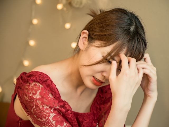 赤いドレスを着て頭を抱える日本人女性