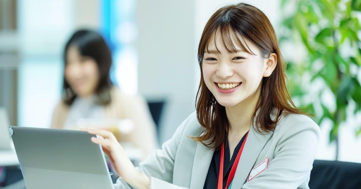 オフィスでノートPCを触りながら笑顔を見せる事務職の女性