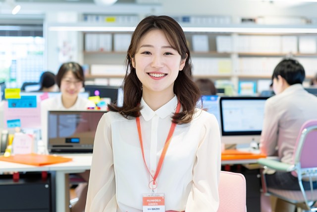 オフィスでIDカードを首にかけた笑顔の女性会社員