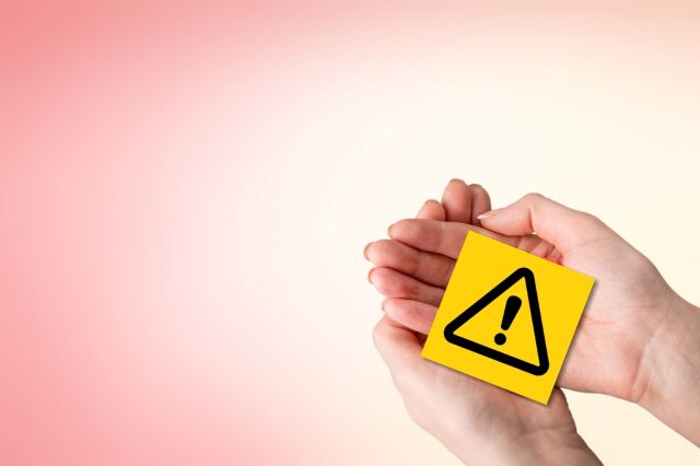 手のひらで注意マークをもつ女性