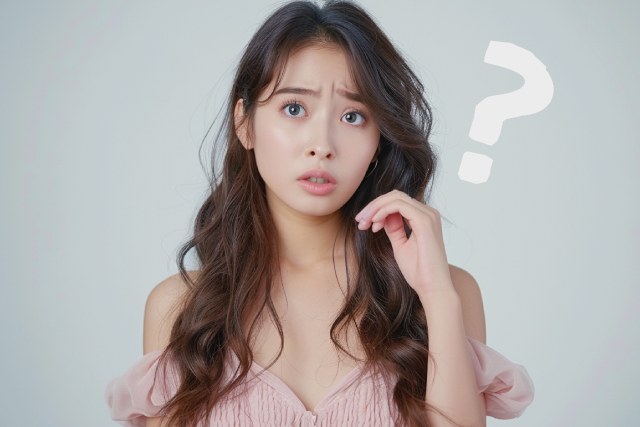 混乱した様子のピンクのオフショルダーのドレスを着た日本人女性