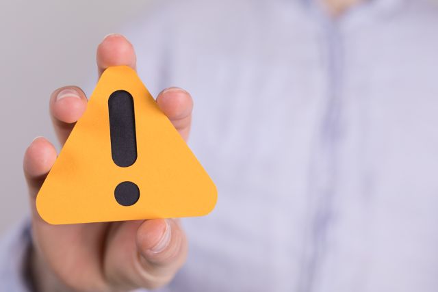 注意マークを持つ男性の手