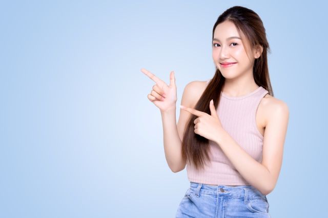 横を指さす女性