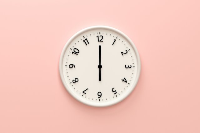 ピンク色の背景とシンプルな壁掛け時計