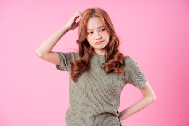 頭に手を当てて悩む女性