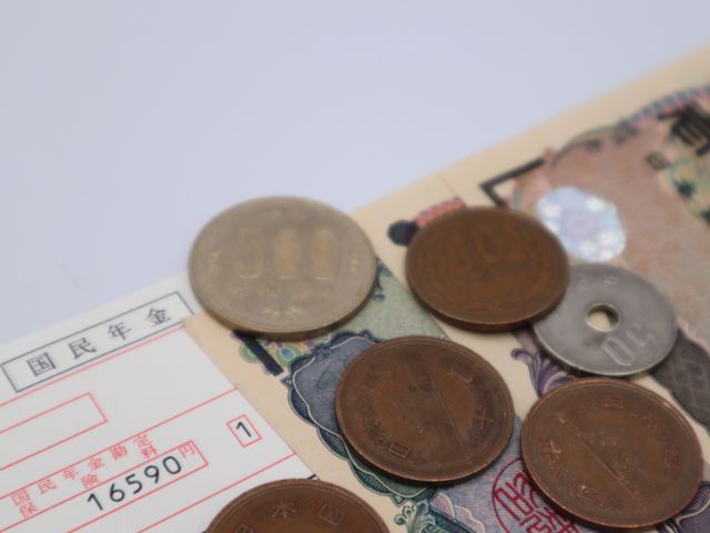国民年金の支払い書と硬貨と一万円札