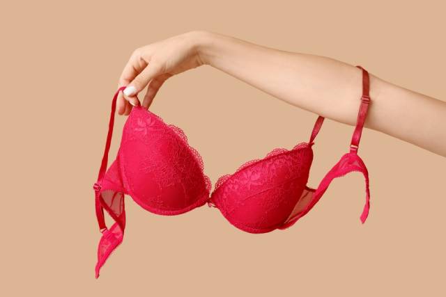 赤いブラジャーを腕にかける女性の手元