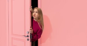 ピンクのドアから覗く女性