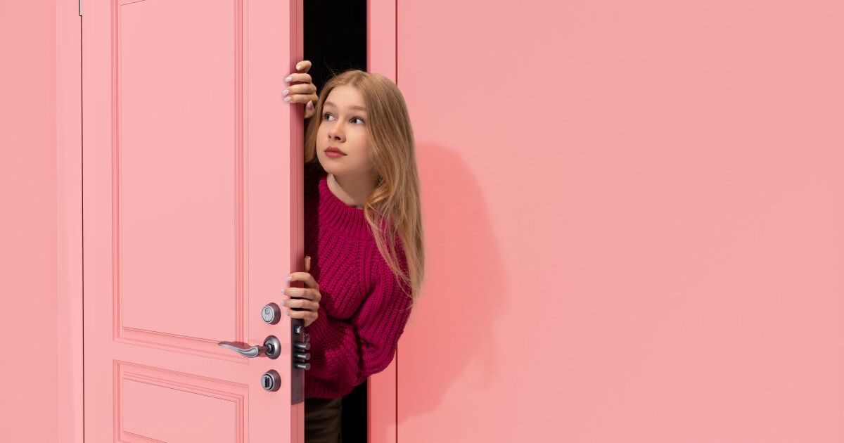 ピンクのドアから覗く女性