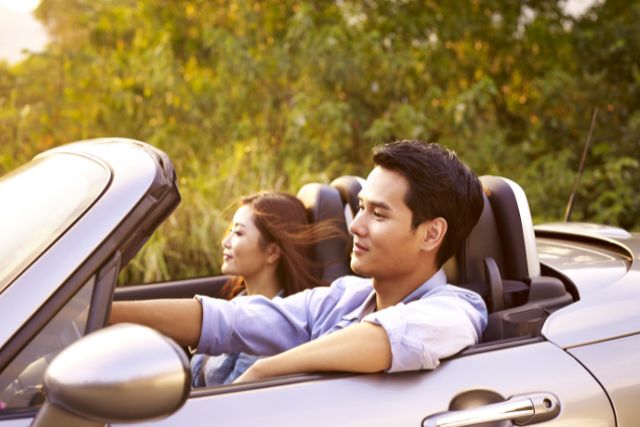オープンカーに乗っている若い男女