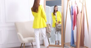 鏡の前に立つ黄色いジャケットの女性
