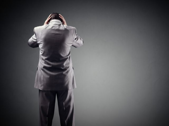 壁に向かって頭を抱えて立っている男性