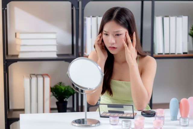 鏡を見ながら悩む女性