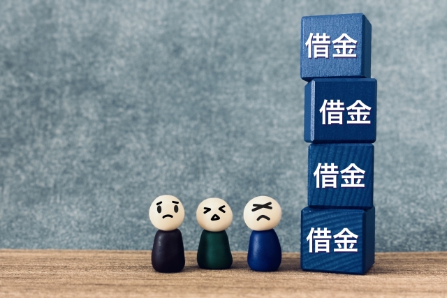 「借金」の文字が入っているブロックと3人の人間の人形
