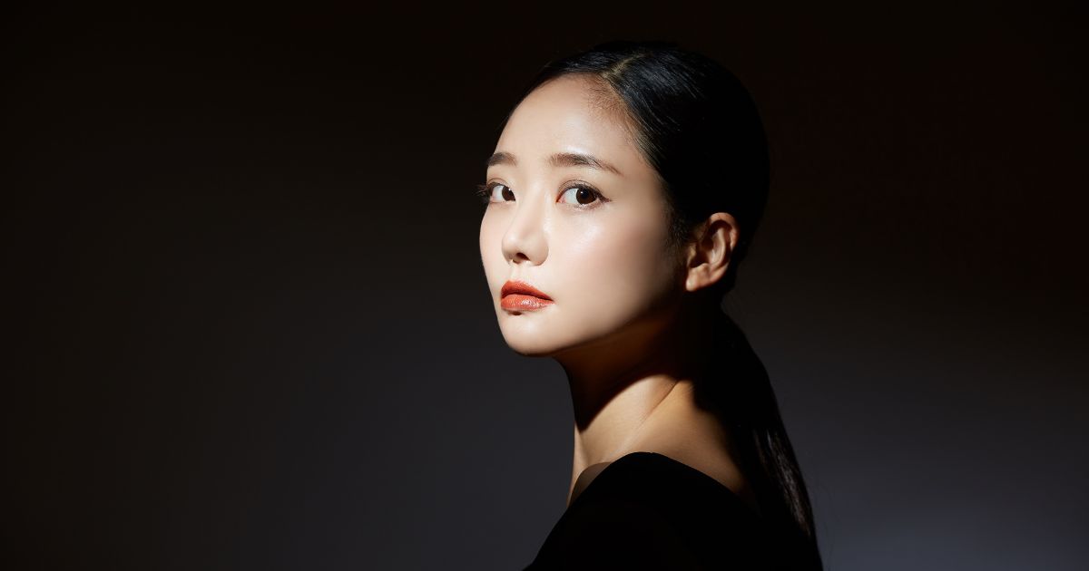 黒い背景に立つ紙をまとめた日本人女性