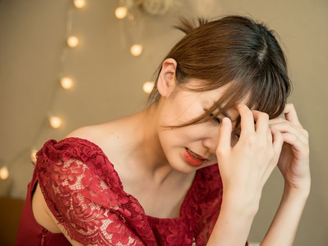 赤いドレスを着て頭を抱える若い日本人女性