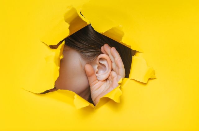 黄色の壁から耳を出している女性