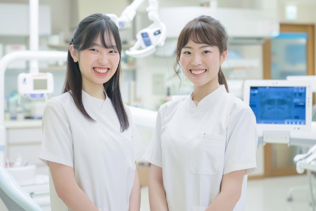二人の歯科衛生士が院内でほほえんでカメラに向かって立っている様子