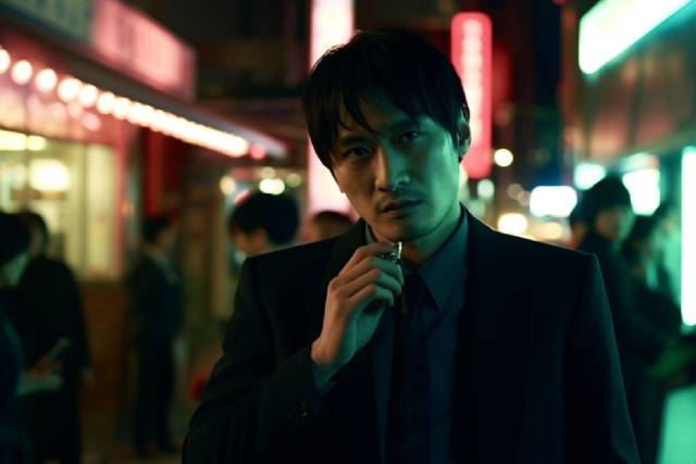 強面の男性が夜の街にたたずんでいる