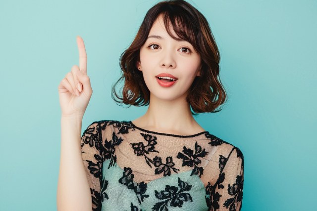緑色のドレスを着て上を指さすショートカットの女性